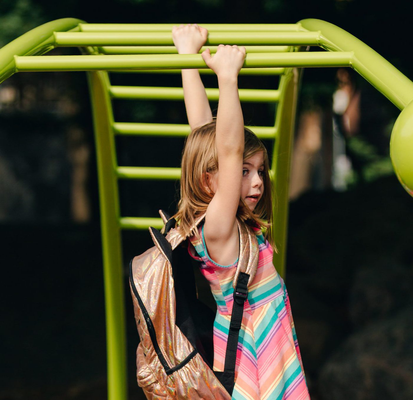 young-girl-swinging-on-bars-with-backpack_4460x4460